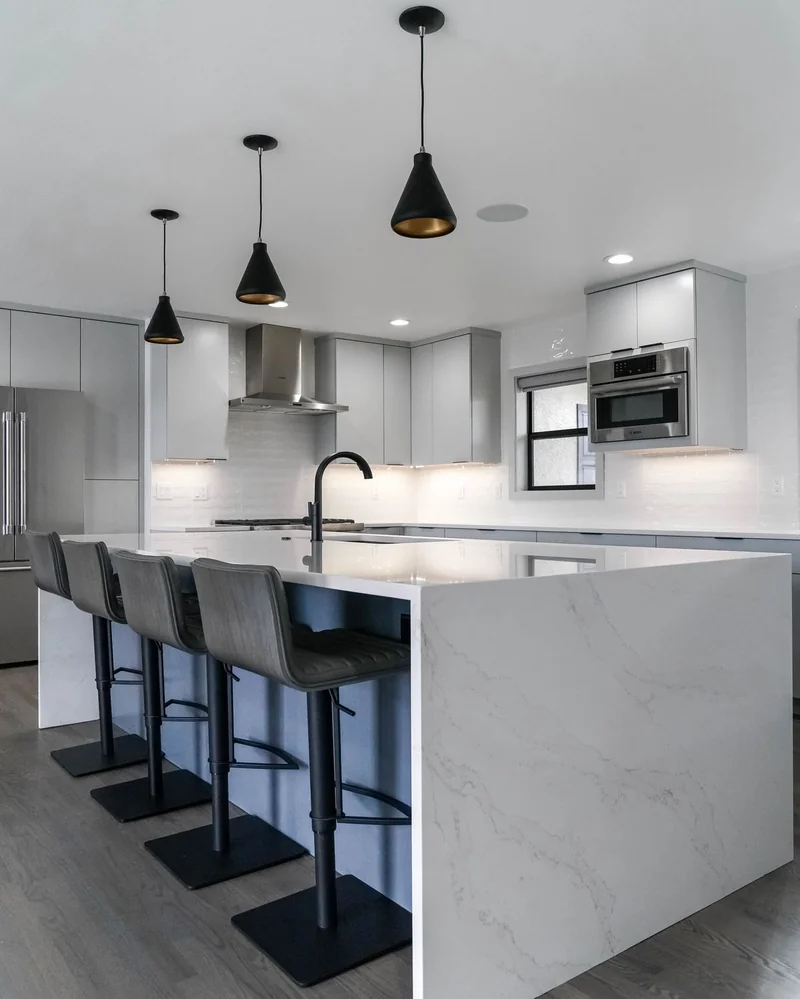 Grey flat-panel kitchen island with four bar stools and black cone pendants