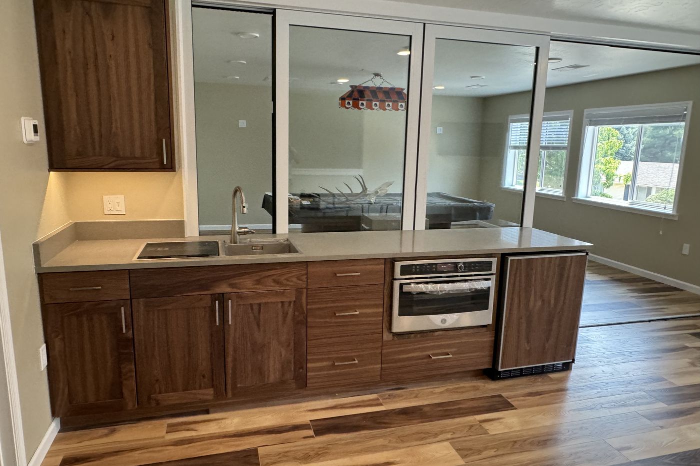 Lower level wet bar with walnut cabinets and a glass wall