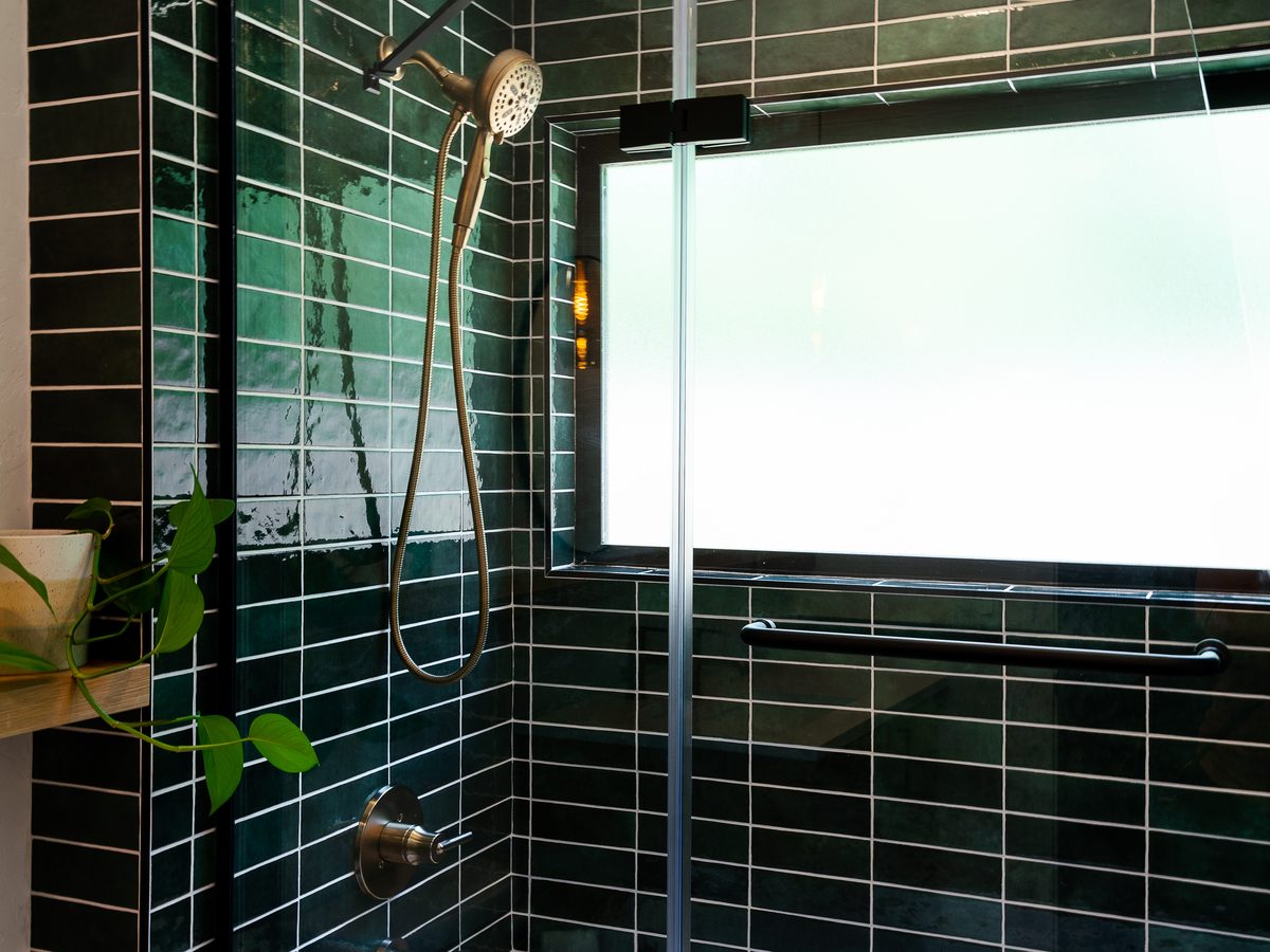 Green stacked tile tub and shower with a hinged glass panel