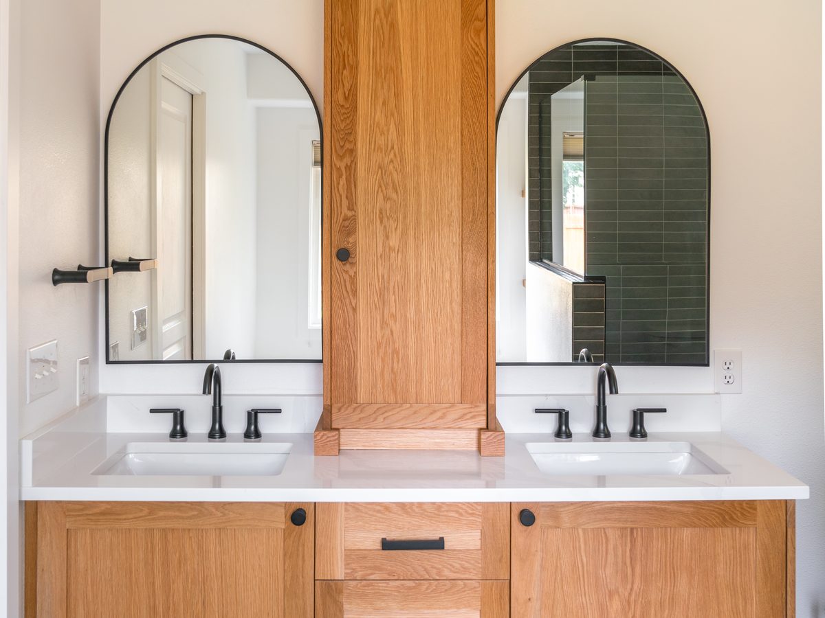 White oak double vanity with a center tower and arched mirrors