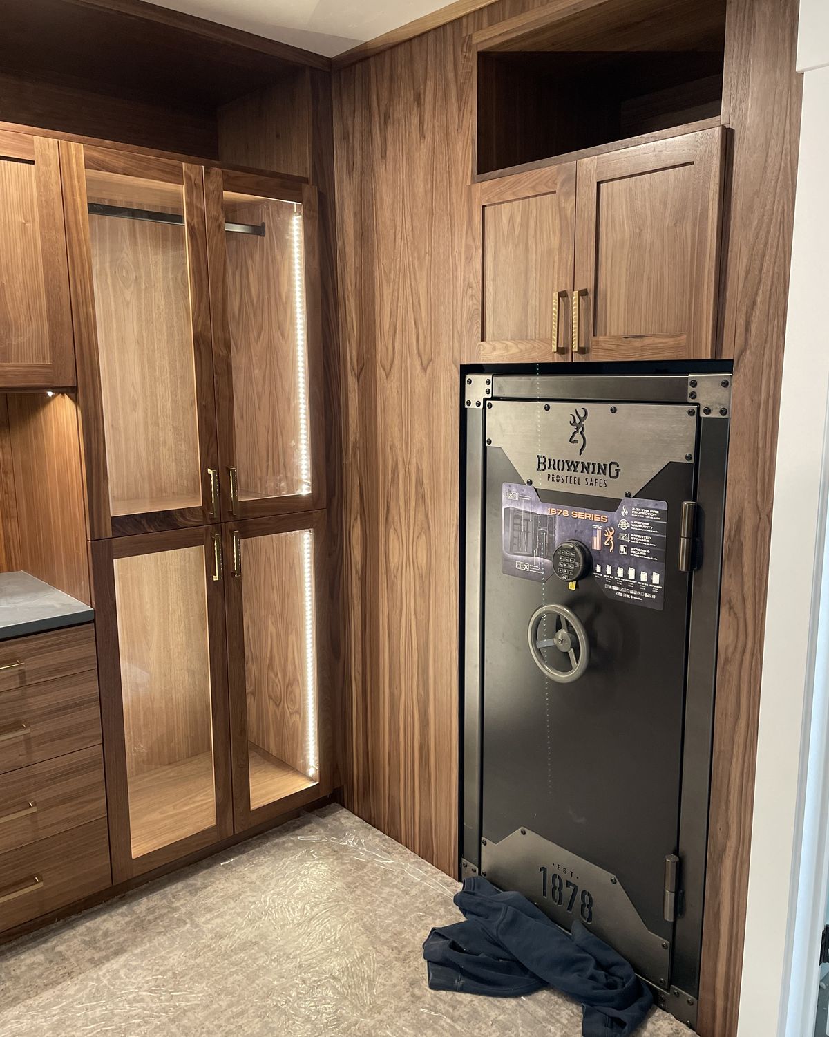 Walnut closet with LED-lit hanging bays and a gun safe recessed into a walnut cabinet alcove