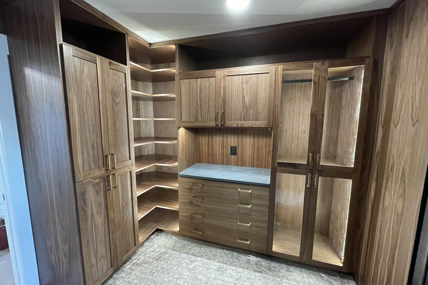 Custom walnut walk-in closet with LED-lit hanging bays and a dresser island