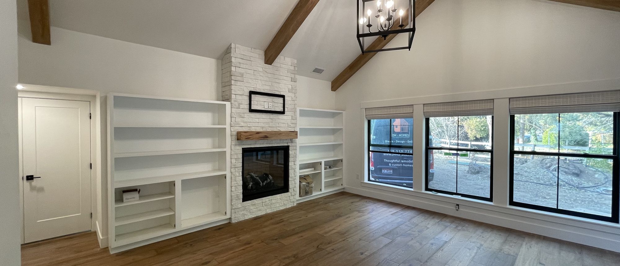 Master bedroom addition in Boise with a vaulted ceiling, butternut wood beams, a painted brick fireplace, and built-in shelving