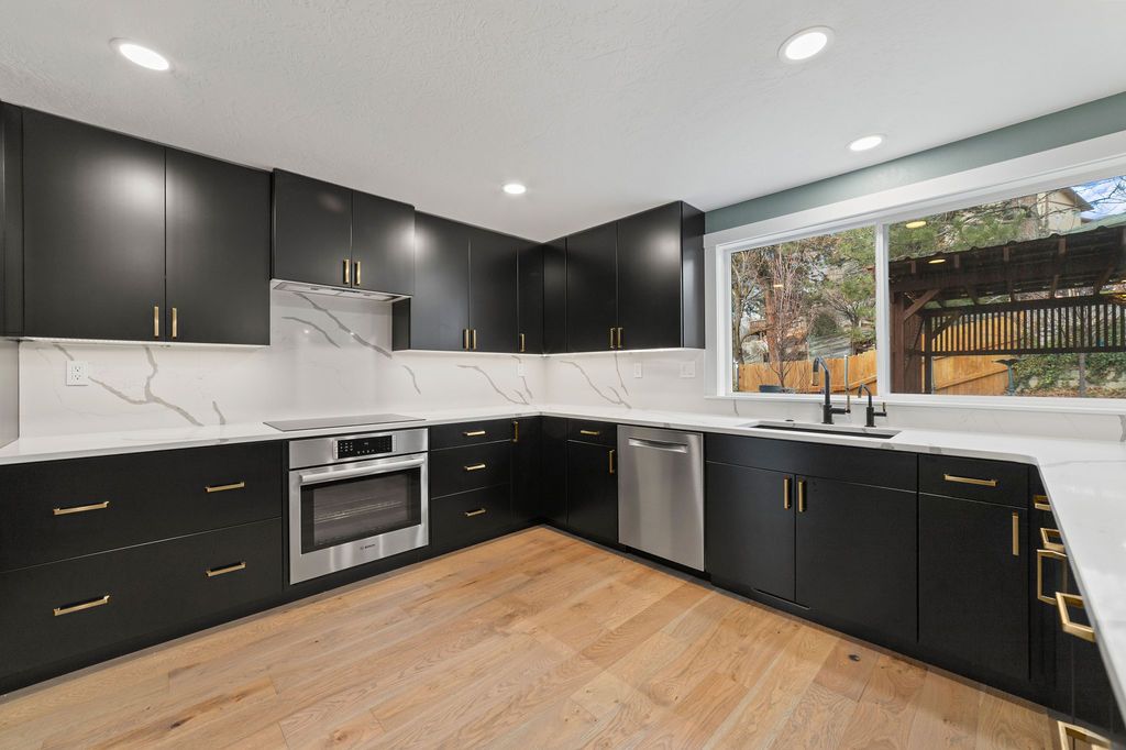 Light oak plank flooring running through a remodeled black cabinet kitchen