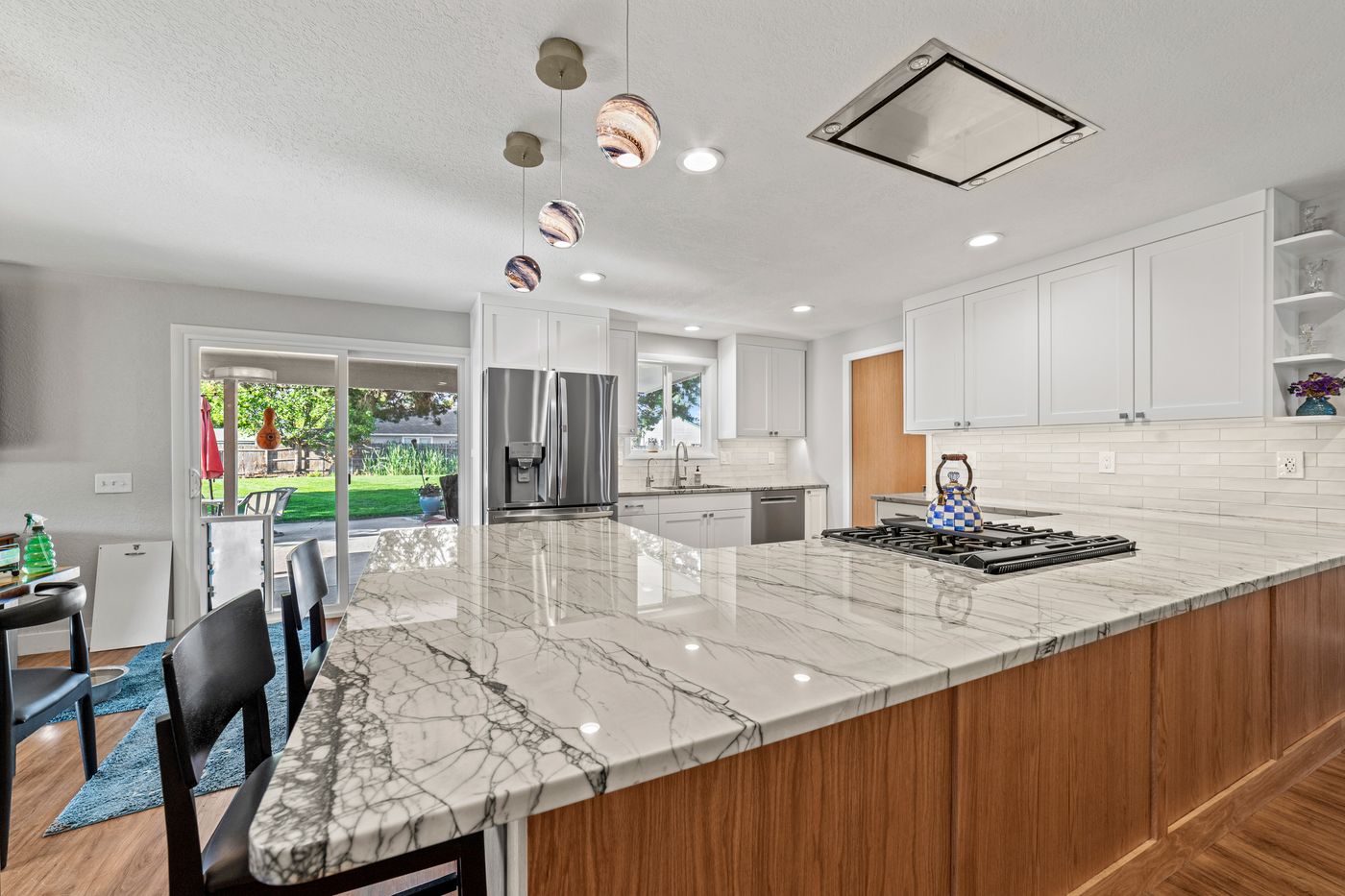 White shaker kitchen with a quartzite peninsula and glass pendants