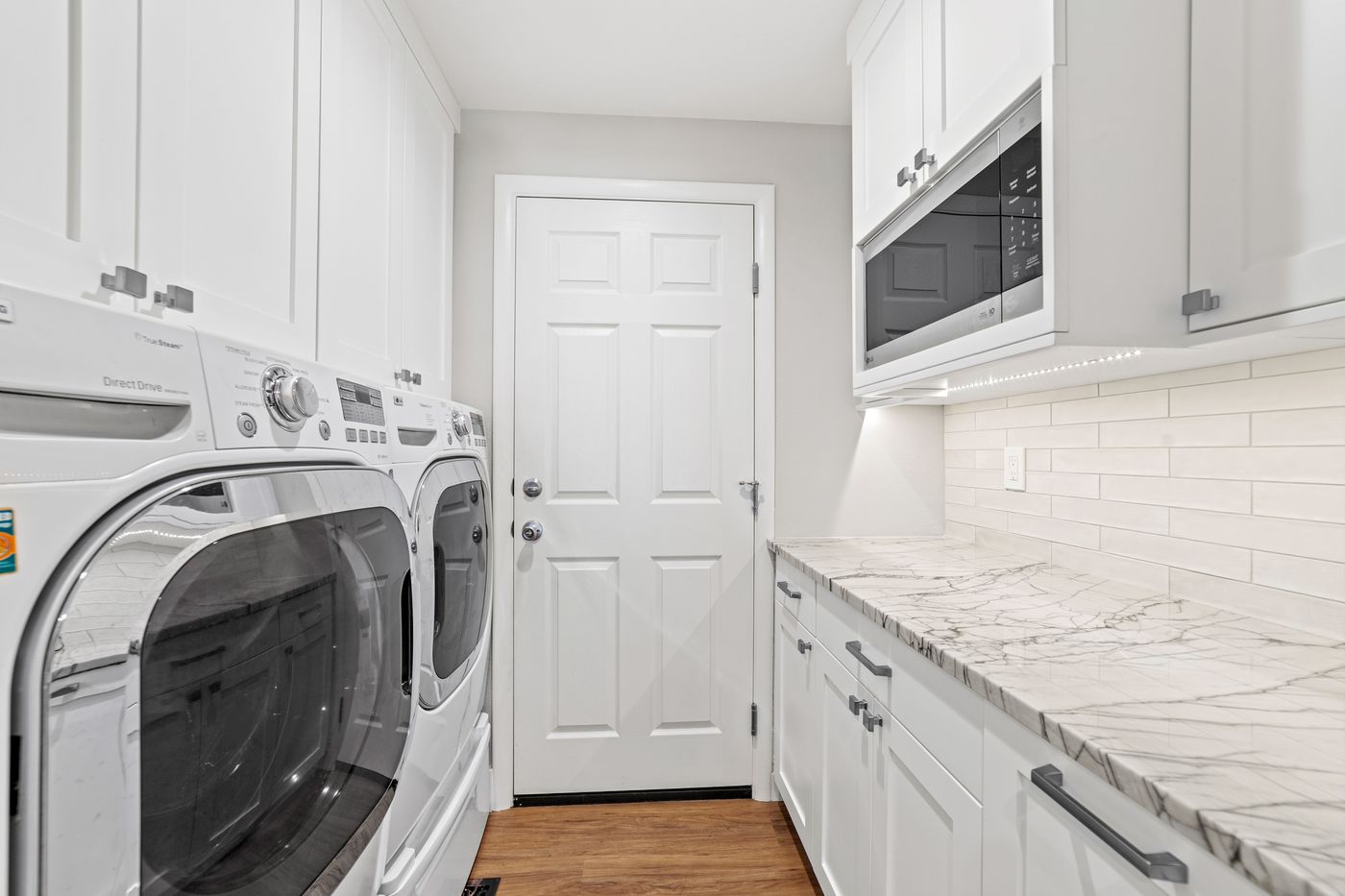 Laundry room with white shaker cabinets and a quartzite counter